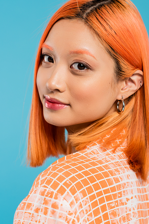 portrait of young asian woman with natural makeup, lip gloss, hoop earrings and short dyed hair looking at camera on blue background, youth, generation z, fashion, casual attire