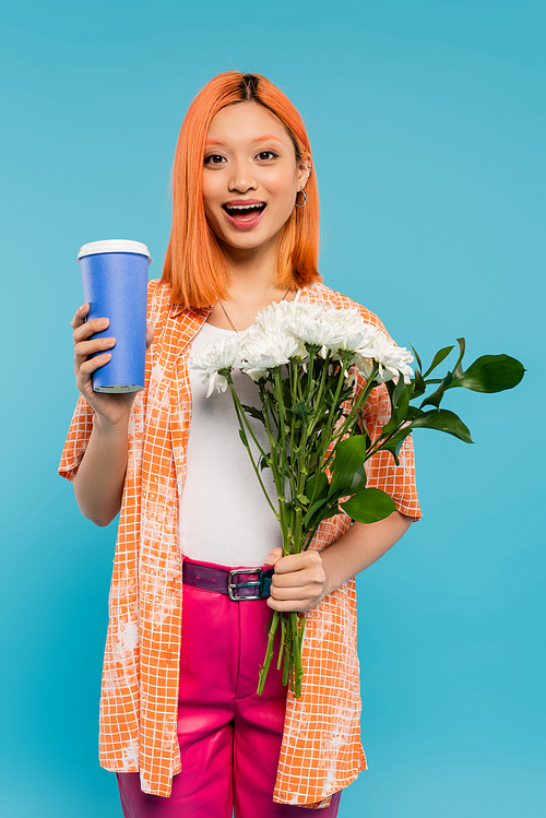 amazed, happy face, asian and young woman with red hair holding coffee to go and bouquet of flowers on blue background, casual attire, generation z, coffee culture, hot beverage, paper cup