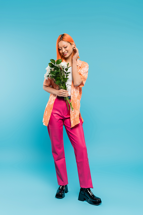 positive vibes, cheerful asian woman with red hair holding white flowers on blue background, casual attire, generation z, floral bouquet, happy face, generation z, youth culture, full length
