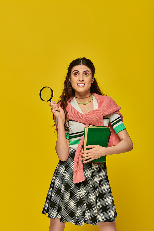 curious young woman holding books and magnifier, zoom, discovery, student in college outfit, smile