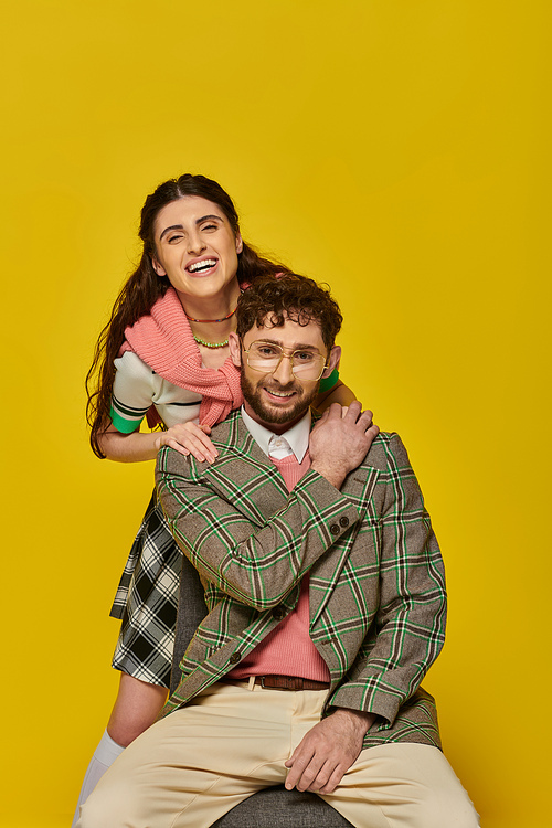 happy students, cheerful man and woman on yellow backdrop, looking at camera, college outfits