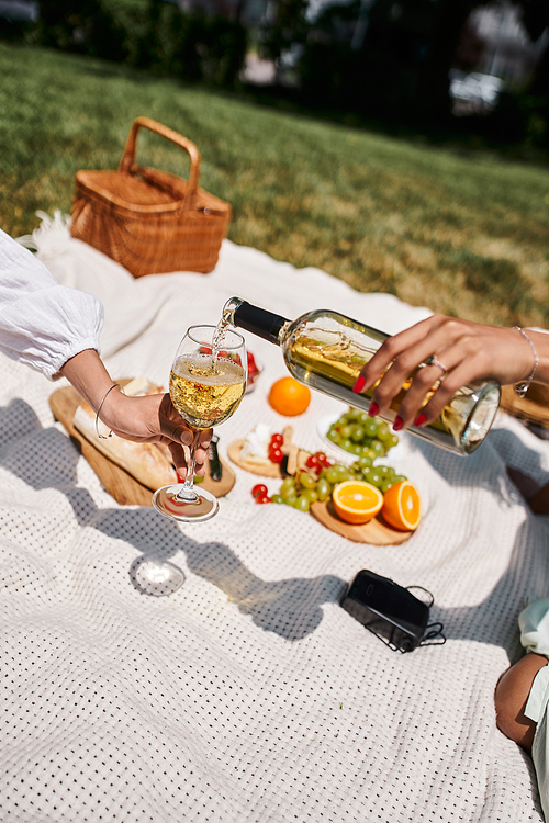 summer picnic, partial view of african american woman holding glass near girlfriend pouring wine