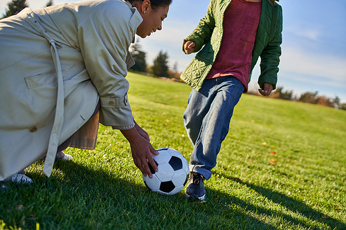 boy standing near ball, african american woman holding soccer ball, football, mother and son