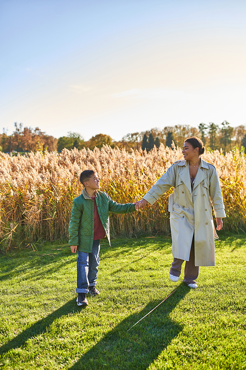 mother and son bonding, holding hands, walking in field, togetherness, motherly love concept, autumn