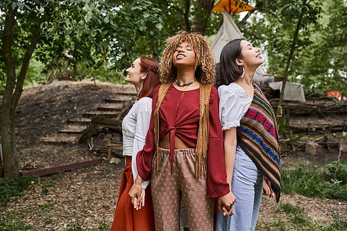 cheerful african american woman holding hands of girlfriends outdoors in retreat center