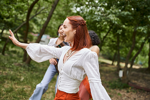 cheerful redhead woman in stylish outfit having fun with girlfriends in retreat center