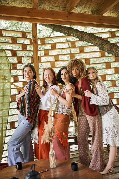multiethnic women in stylish boho clothes standing and looking at camera in retreat center