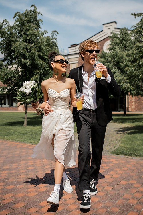 happy interracial couple, wedding attire, sunglasses, orange juice, bouquet, wedding in city