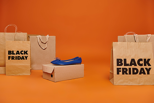 ballet flats on carton box near shopping bags with black friday letters on orange background