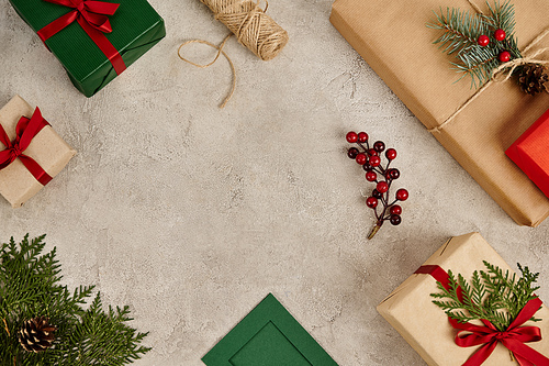 presents with red ribbons and pine branches with holly berries on grey textured backdrop, Christmas