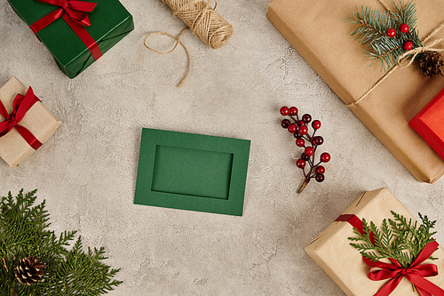 green greeting card and near gift boxes with pine branches and holly berries, Christmas background