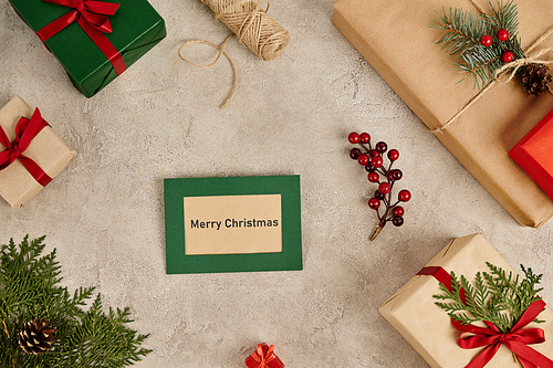 Merry Christmas greeting card near gift boxes and festive Christmas decor on grey textured surface