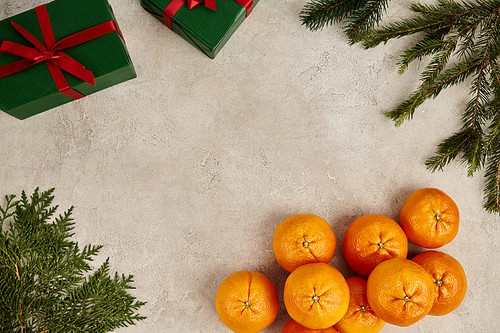 frame with ripe tangerines and green gift boxes near juniper and pine branchers on textured surface