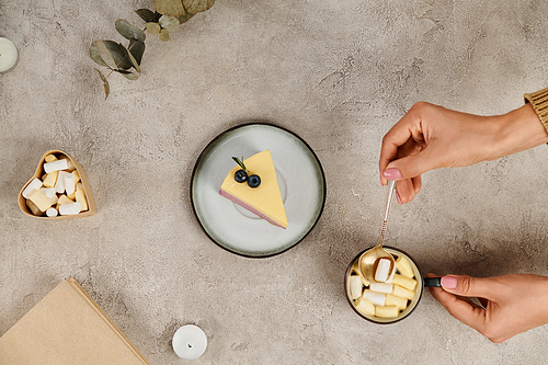 cropped view of woman with tea spoon near hot chocolate with marshmallows and Christmas pudding