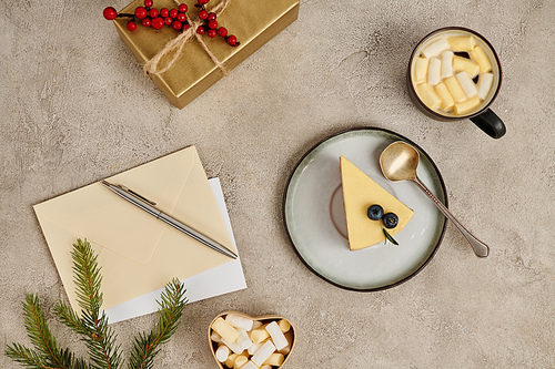 Christmas pudding and hot chocolate with marshmallows near envelopes and pen on textured backdrop