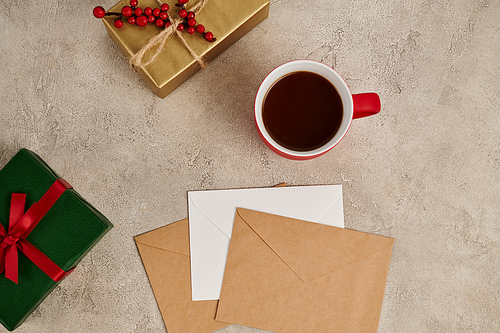 hot chocolate near multicolored gift boxes and envelopes on grey textured Christmas backdrop