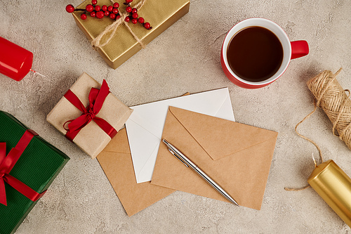 traditional hot chocolate near envelopes and gift boxes with candles on grey texture, Christmas