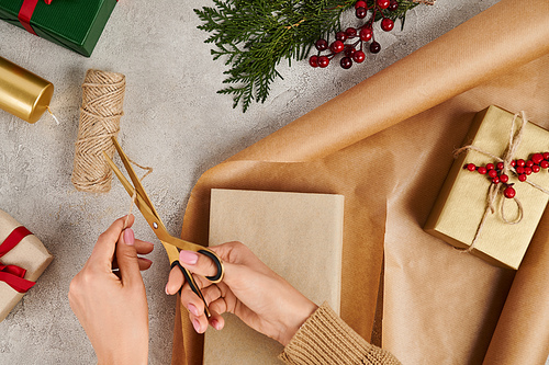 cropped view of woman with scissors cutting twine near gift box and craft paper, diy Christmas gifts