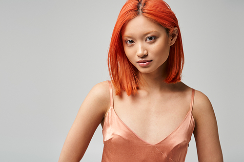 portrait of beautiful young asian woman in silk slip dress posing on grey backdrop, natural makeup