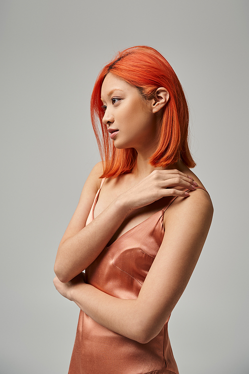 portrait of beautiful young asian woman in silk slip dress looking away on grey background