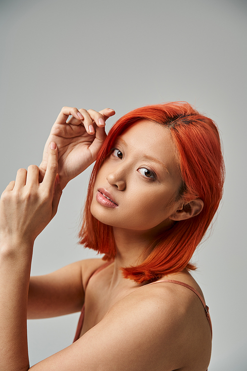 portrait of pretty asian woman with dyed hair looking at camera on grey background, natural beauty