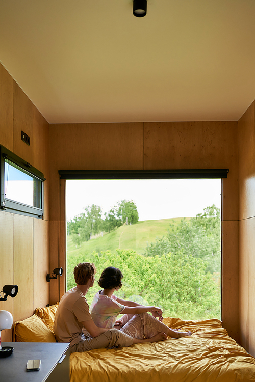 couple enjoying beautiful view on green trees and resting together in country house, serenity