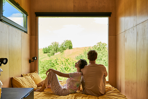 asian woman sitting on bed and leaning on shoulder of boyfriend, relaxing together in country house