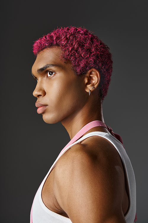 portrait of young handsome man with pink hair and earrings posing in profile, fashion and style