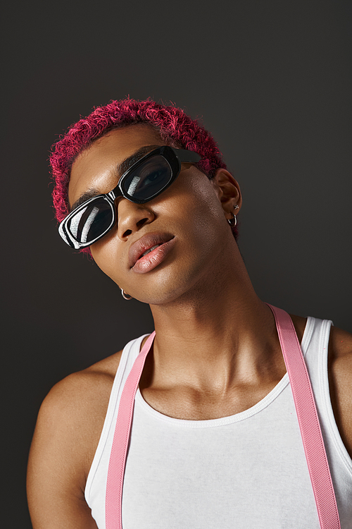 portrait of stylish male model with pink hair wearing sunglasses in front of camera, fashion concept