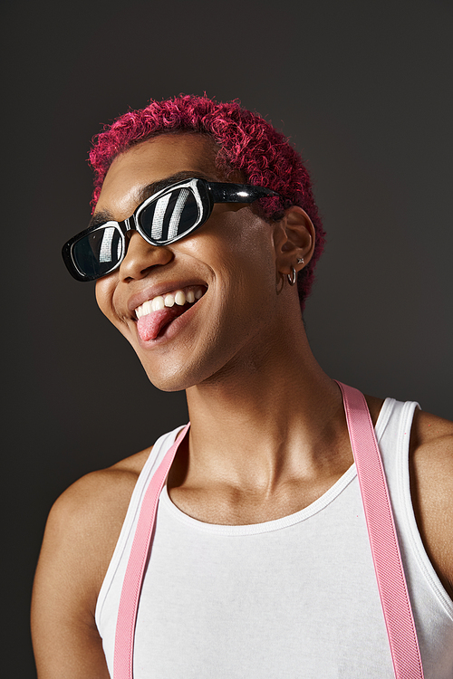 playful stylish man with pink hair in voguish sunglasses sticking out his tongue, fashion concept