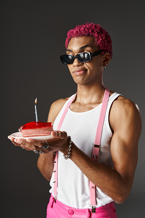 handsome african american man in sunglasses posing with cake and burning candle, fashion concept