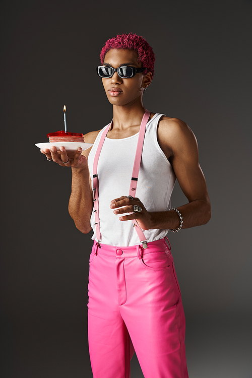 good looking man in sunglasses posing with delicious cake and touching suspenders, fashion concept