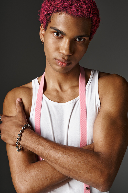 portrait of young stylish man with pink hair posing with slightly crossed arms, fashion concept