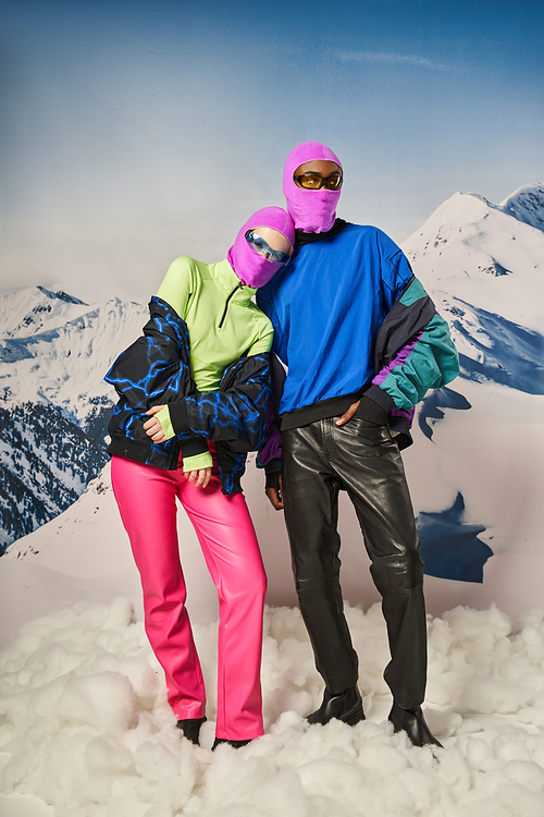 beautiful couple posing together wearing pink balaclavas and stylish sunglasses, winter concept