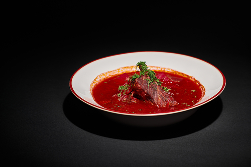 eastern European cuisine, traditional Ukrainian borsch with beef in ceramic bowl on black backdrop