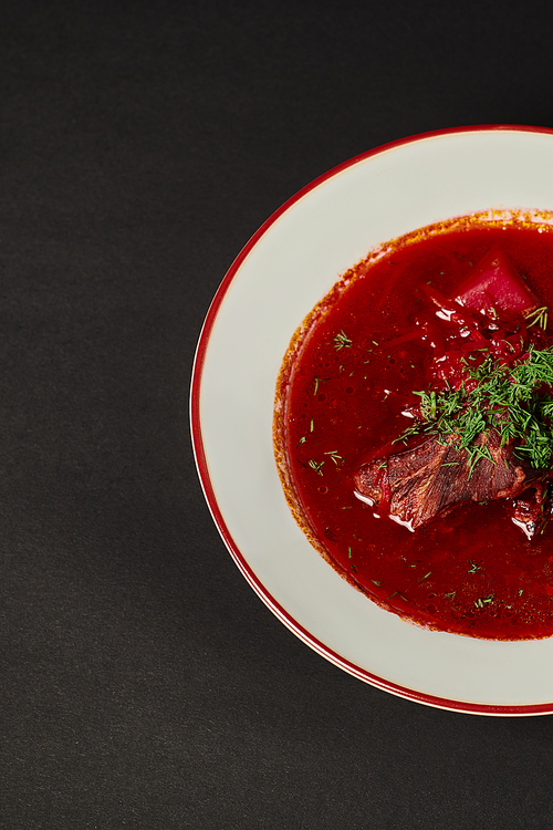 eastern European cuisine, traditional Ukrainian borsch with beef in ceramic bowl on black, banner