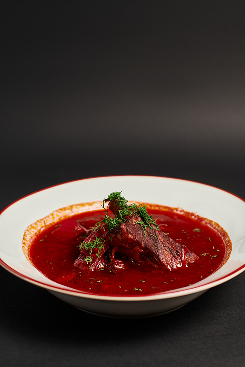 homemade meal, traditional Ukrainian borsch with beef in ceramic bowl on black backdrop