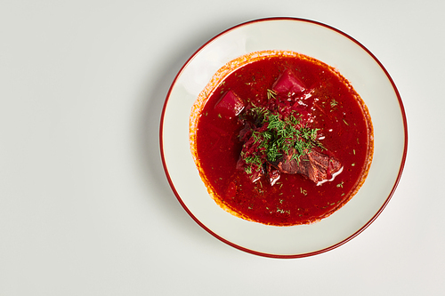 eastern European cuisine, traditional Ukrainian borsch with beef in ceramic bowl on grey backdrop