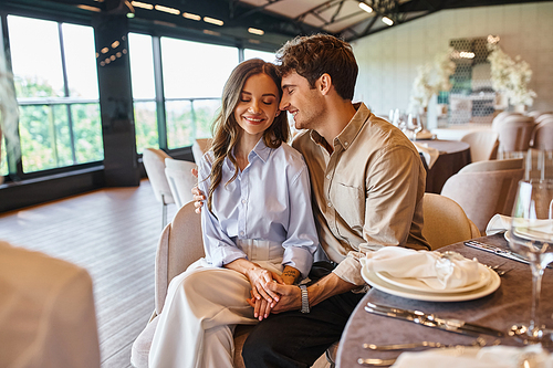 delighted couple in love smiling with closed eyes near event manager in modern wedding hall