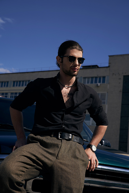 vertical shot of elegant man with beard and sunglasses wearing black casual attire, sexy driver