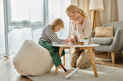 mother and child with prosthetic leg drawing on paper with colorful pencils together, quality time