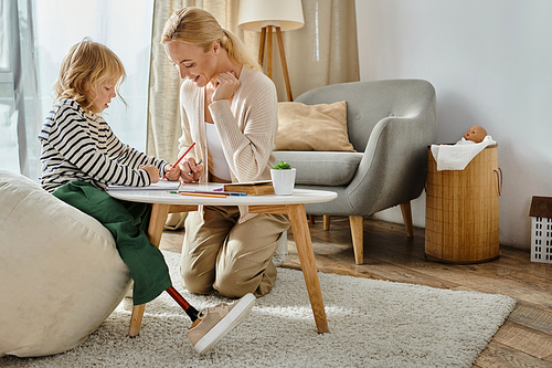 woman and girl with prosthetic leg drawing on paper with colorful pencils together, quality time