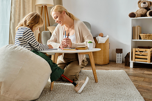 mother and child with prosthetic leg drawing on paper with colorful pencils, quality time