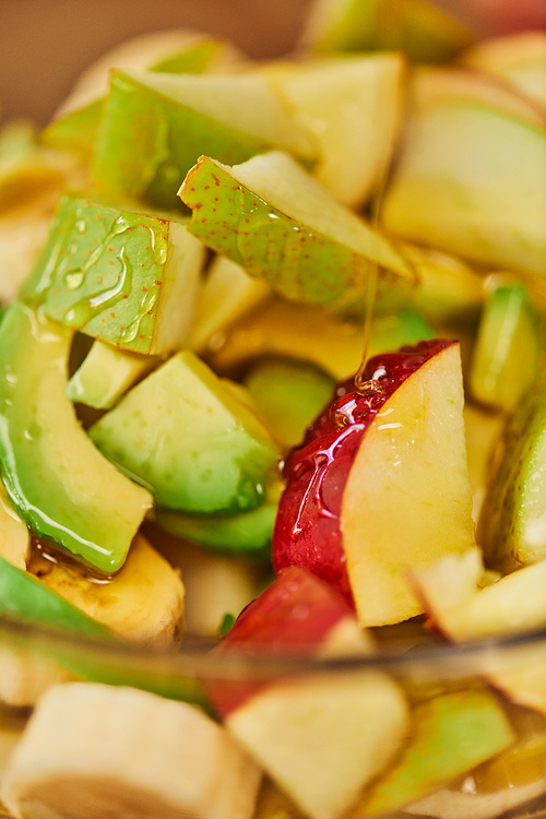 close up of delicious fruit salad with apples, pears and avocado with honey, vegetarian backdrop