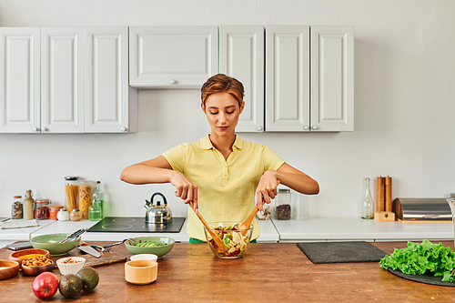 vegetarian woman mixing fresh fruit salad in modern kitchen, healthy and wholesome eating concept