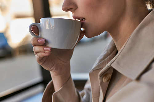 cropped close up shot of young woman with perfect skin drinking coffee in cafe, cup of cappuccino
