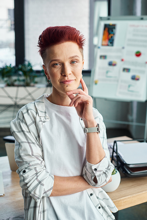 professional headshot of stylish non-binary business person looking at camera in modern office