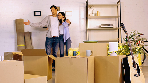 blurred man hugging girlfriend and showing new home