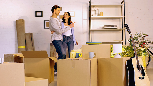 blurred man hugging amazed girlfriend and showing new home