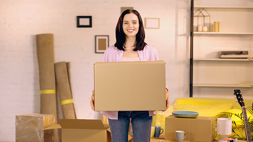 happy woman holding carton box in new home